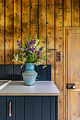 Cut flowers in vase on worktop in woodclad Cirencester barn conversion Gloucestershire UK