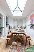 Bench seats and table below skylight in dining room extension of Devon cottage