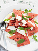 Sliced watermelon and cheese with fork and spoon on plate Derwent Water, Cumbria, England UK