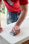 Mann arbeitet mit Schleifklotz auf einem Sideboard in einem britischen Haus