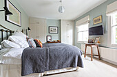 Graue Decke in einem hellgrünen Schlafzimmer mit wandmontiertem Fernseher Reading, Berkshire, England UK