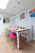 Dining table made from reclaimed wood with colourful chairs in Guildford cottage Surrey UK