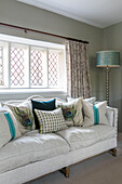 White sofa with teal cushions in leaded glass window of Grade II listed Jacobean house Alton UK