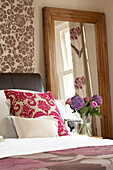 Tapete und Kissen mit Schafsmuster im Londoner Schlafzimmer mit Schnittblumen