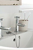Tap fittings on washbasin with ceramic toothbrush holder