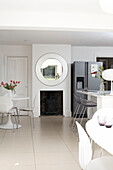 Circular mirror above wood burning stove in London kitchen