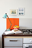 Schreibtischlampe auf Küchenarbeitsplatte mit offenem Rezeptbuch in einem Haus auf der Isle of Wight, UK