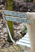 Folding chair with handwriting 'Rest and be thankful' in garden, St Lawrence, Isle of Wight, UK