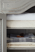 Folded blankets and bed covers scented with pinecone and cinnamon sticks in Isle of Wight home, UK