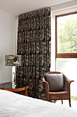 Wicker chair and curtains at window in bedroom of contemporary Isle of Wight home UK