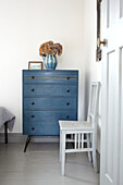 Upcycelter Stuhl mit blauer Kommode im Schlafzimmer eines Hauses in Brighton, East Sussex UK
