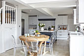Ghost chairs at dining table in open plan kitchen with flagstone floor and Shaker style units Buckinghamshire UK