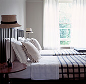 Twin beds in guest bedroom with straw hat bedside lamps and open window