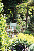 Gartenstuhl auf der Terrasse inmitten von Gartenlaub und Blumen