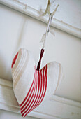 Close up of red and white striped fabric heart sachet on coat hook