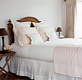 Close up of vintage wooden bed dressed in pink and white fine bed linen