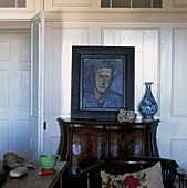 Detail of antique credenza and artworks against panelled wall in the living room