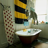 Wäschetrockner mit Wäsche, die über der Badewanne in einem weißen Badezimmer trocknet