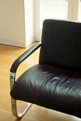 Close up Sixties style black leather sofa with chromed steel frame