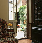 View of patio garden with lead planters through glass panelled door of sitting room in London town house