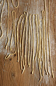 Freshly prepared noodles laid out on a floured wooden surface in a kitchen