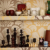 Close up of the museum cupboard lined with Osborne and Little wallpaper housing a collection of artifacts from around the world