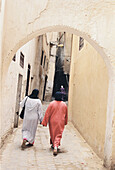 Two local women walking up a narrow street in the medina in Fez Morocco