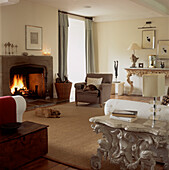 Living room with lit open fire rug wood floors and armchairs in neutral colours