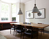 Contemporary dining room with large table hanging ceiling lights and large window