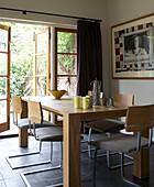 Esstisch aus hellem Holz im grau gefliesten Gartenzimmer eines Stadthauses in London, UK