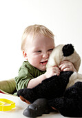Two year old boy squeezes his toy panda