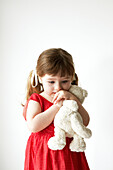 Young girl in red dress holding a teddybear