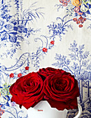 Rote Rosen und blaue Blumentapete