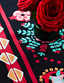 Rote Rosen auf einem gemusterten Tischtuch