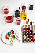 Kartontablett mit mehrfarbigen Eiern und verschiedenen Töpfen mit Farbe und Färbemitteln