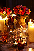 Christmas place setting with vases of roses and candles on a table top