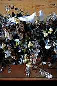 Detail of festive garland draped over the mantlepiece with doves and pine cones amongst foliage