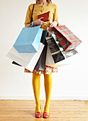 Woman stands holding an assortment of shopping bags