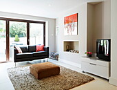 Zweisitziges schwarzes Ledersofa im Wohnzimmer eines Londoner Stadthauses, England, UK