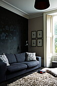 Schwarzes Sofa mit gemusterter Tapete in einem Stadthaus in London, England, UK