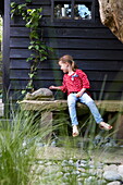 Mädchen sitzt im Garten eines Londoner Stadthauses, England, UK