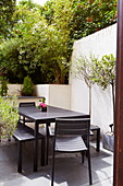 Bench seat and chairs at garden table of London townhouse, England, UK