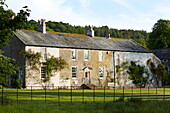 Fenced garden and stone exterior of rural Cumbrian farmhouse, England, UK