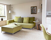 Lindgrünes Sofa und Kissen mit passenden Pendelleuchten in einem modernen Haus in London, England, UK