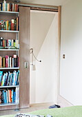 Bücherregal und Schiebetür im Schlafzimmer in einem modernen Haus in London, England, UK