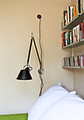 Wandleuchte mit Bücherregal in einem modernen Schlafzimmer in London, England, UK