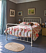 Geblümte Bettdecke auf einem Bett mit Metallrahmen und Kunstwerken in einem Haus der Familie in Rye, East Sussex, England, Vereinigtes Königreich