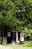 Schwarz gestrichenes Gartenhaus unter Bäumen in Rye, East Sussex, England, UK