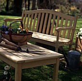 Wooden table and branch with basket of flowers and gardening tools