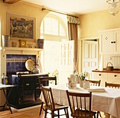Chairs set at table in country kitchen with sunlit open back door